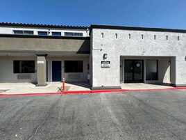 Un hotel con area parcheggio riservata agli ospiti, ingresso dell'edificio e cartello che indica il parcheggio per clienti.