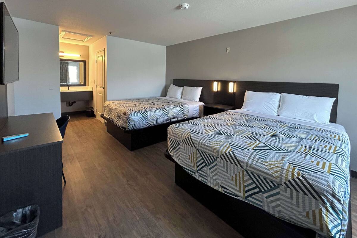 Una habitación de hotel con dos camas, un escritorio y un baño.