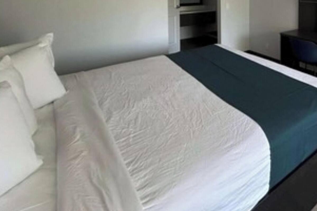 Una habitación de hotel con una cama grande, un escritorio y un armario.