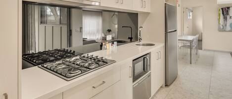 A modern kitchen with white cabinets, stainless steel appliances, and a large island with a sink.