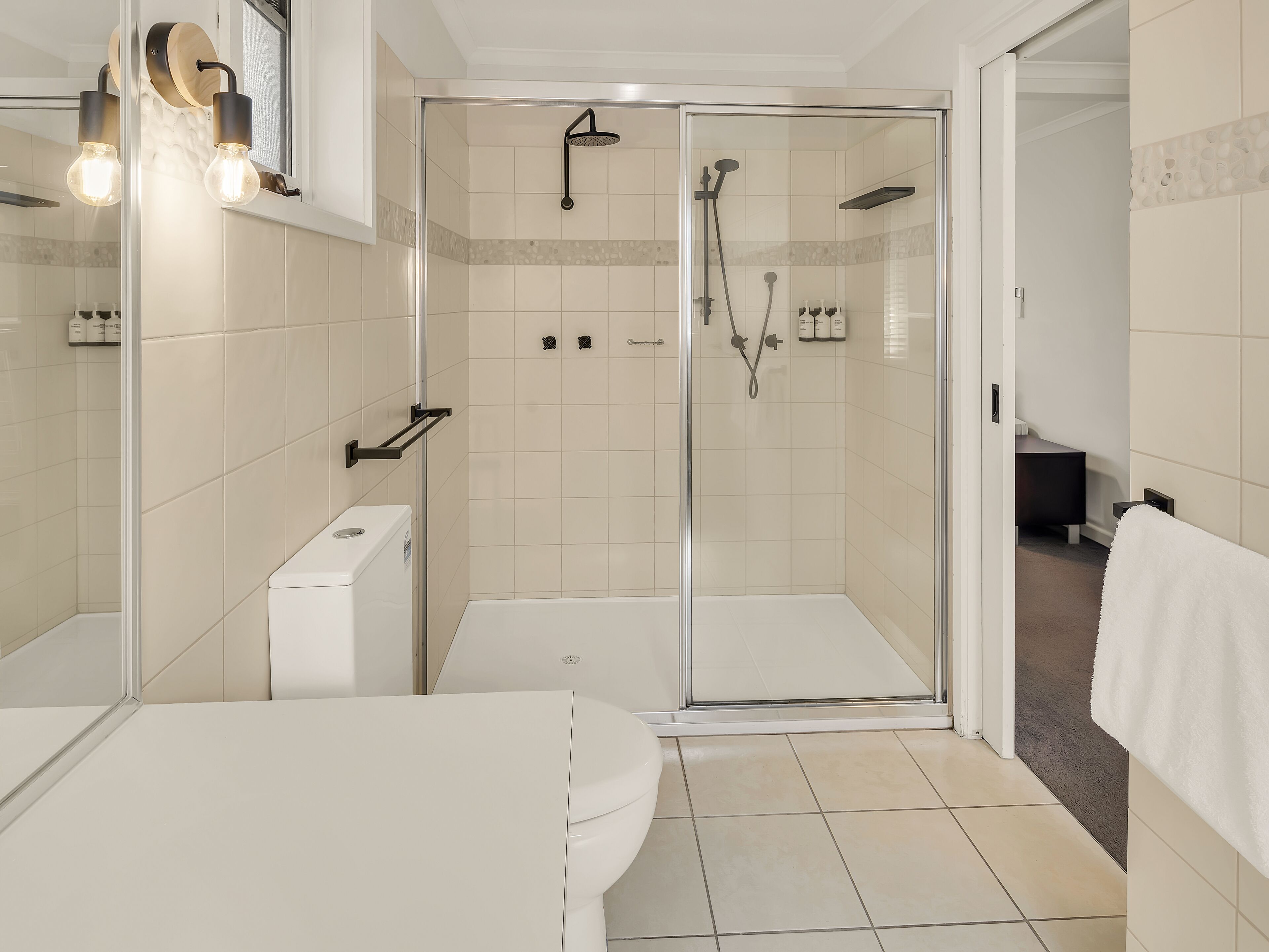 Ein modernes Badezimmer mit einer Duschkabine aus Glas, einer Toilette und einem Waschbecken.