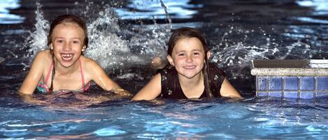 Dos personas en una piscina con agua salpicando a su alrededor.