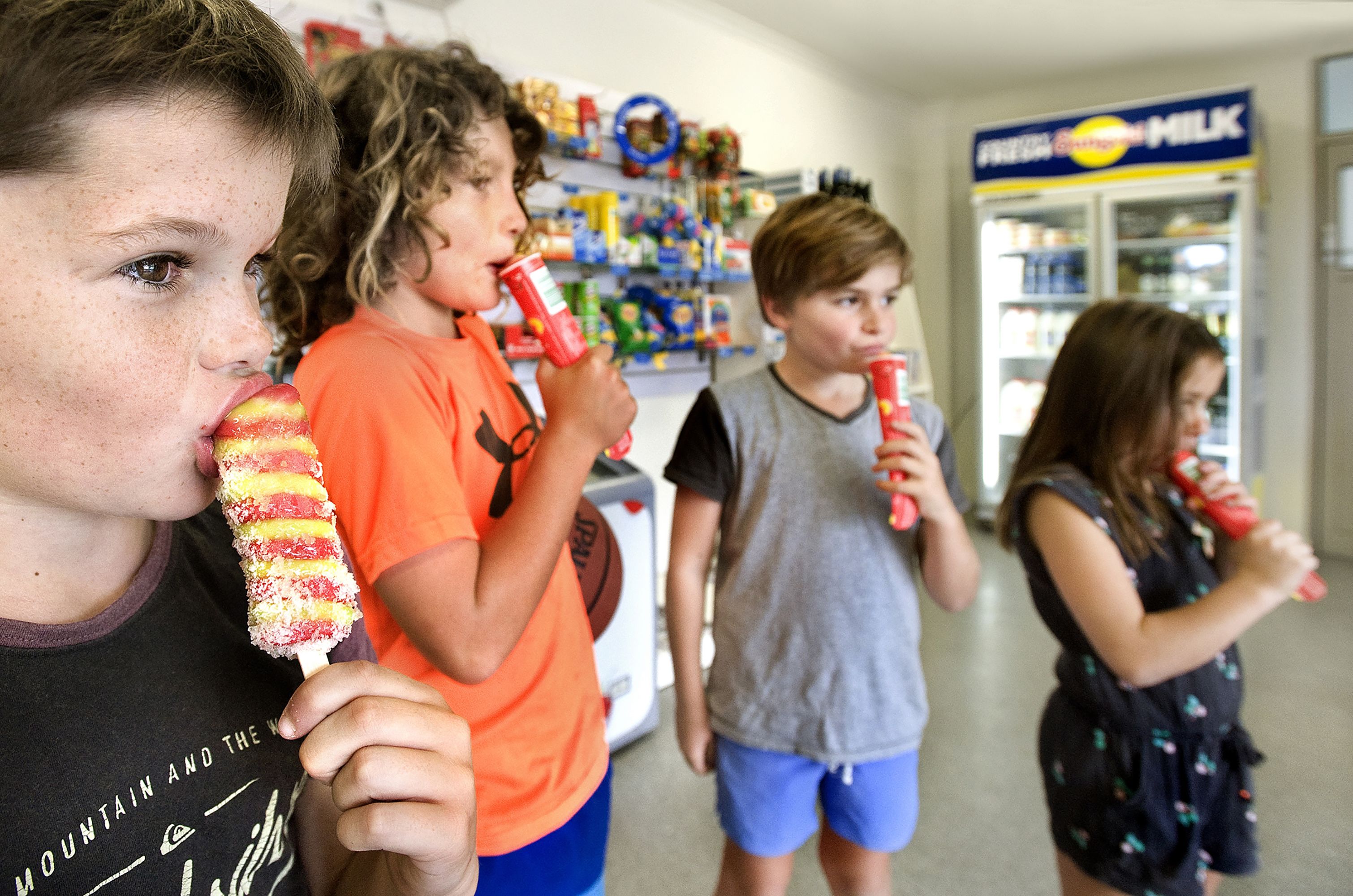 A group of children holding red cups, likely in a store or mall.