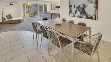 A dining area with a table and chairs, a sofa, and a large abstract painting on the wall.