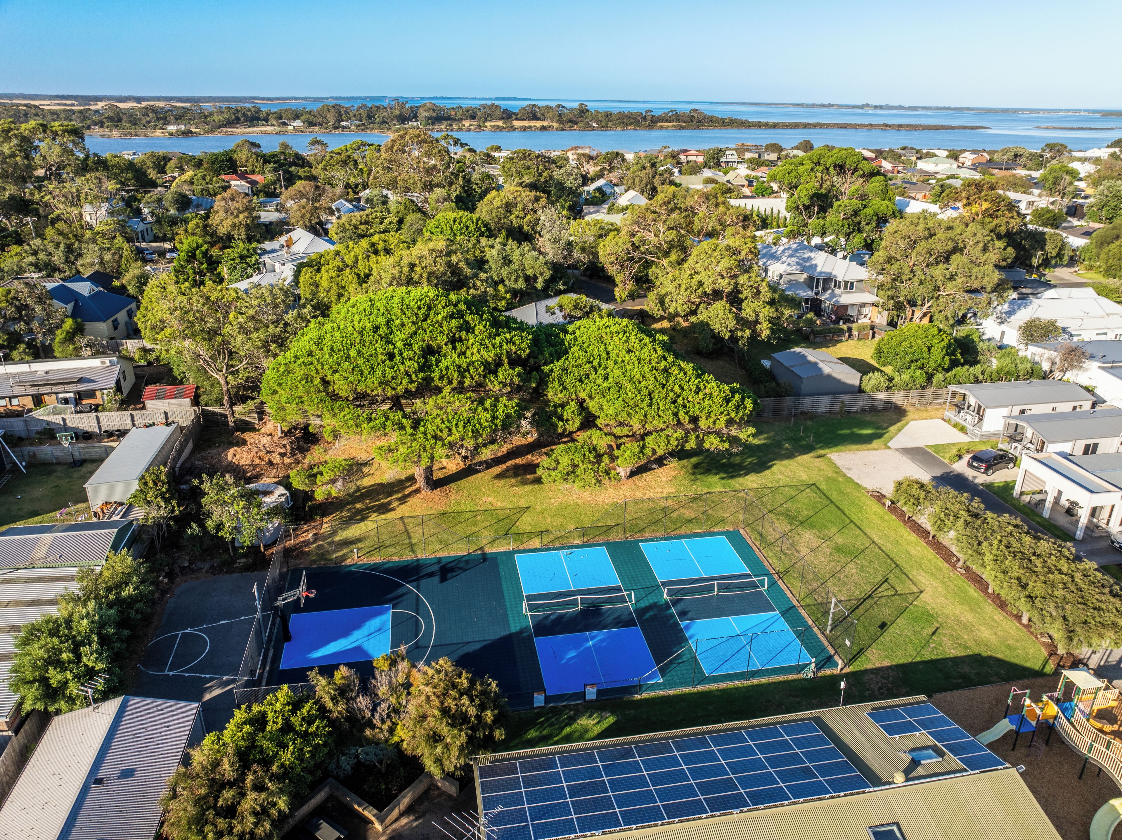 A residential area with houses, a basketball court, and solar panels.