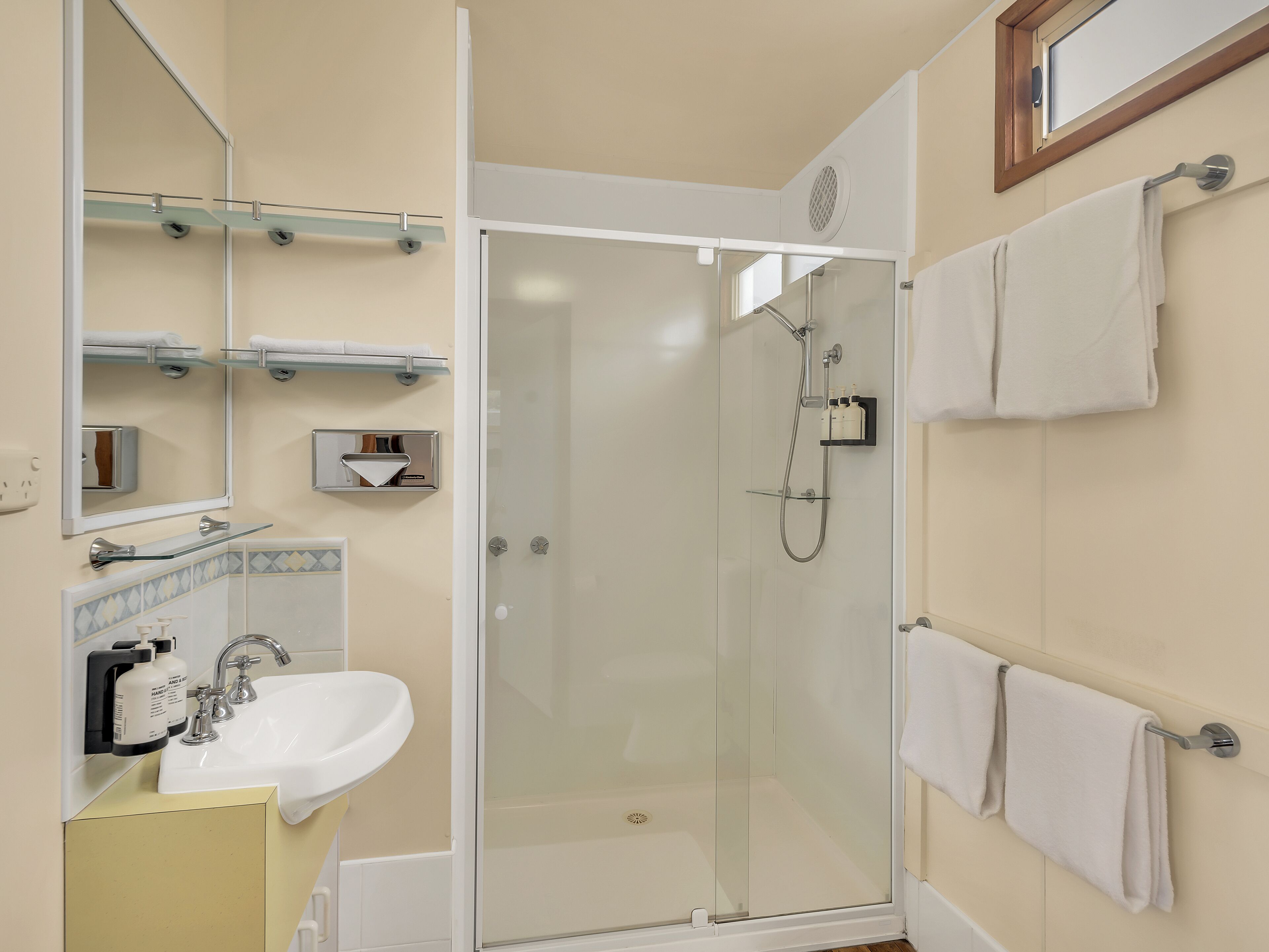 Une salle de bain moderne avec une douche à parois de verre, un lavabo avec un miroir et des porte-serviettes fixés au mur.