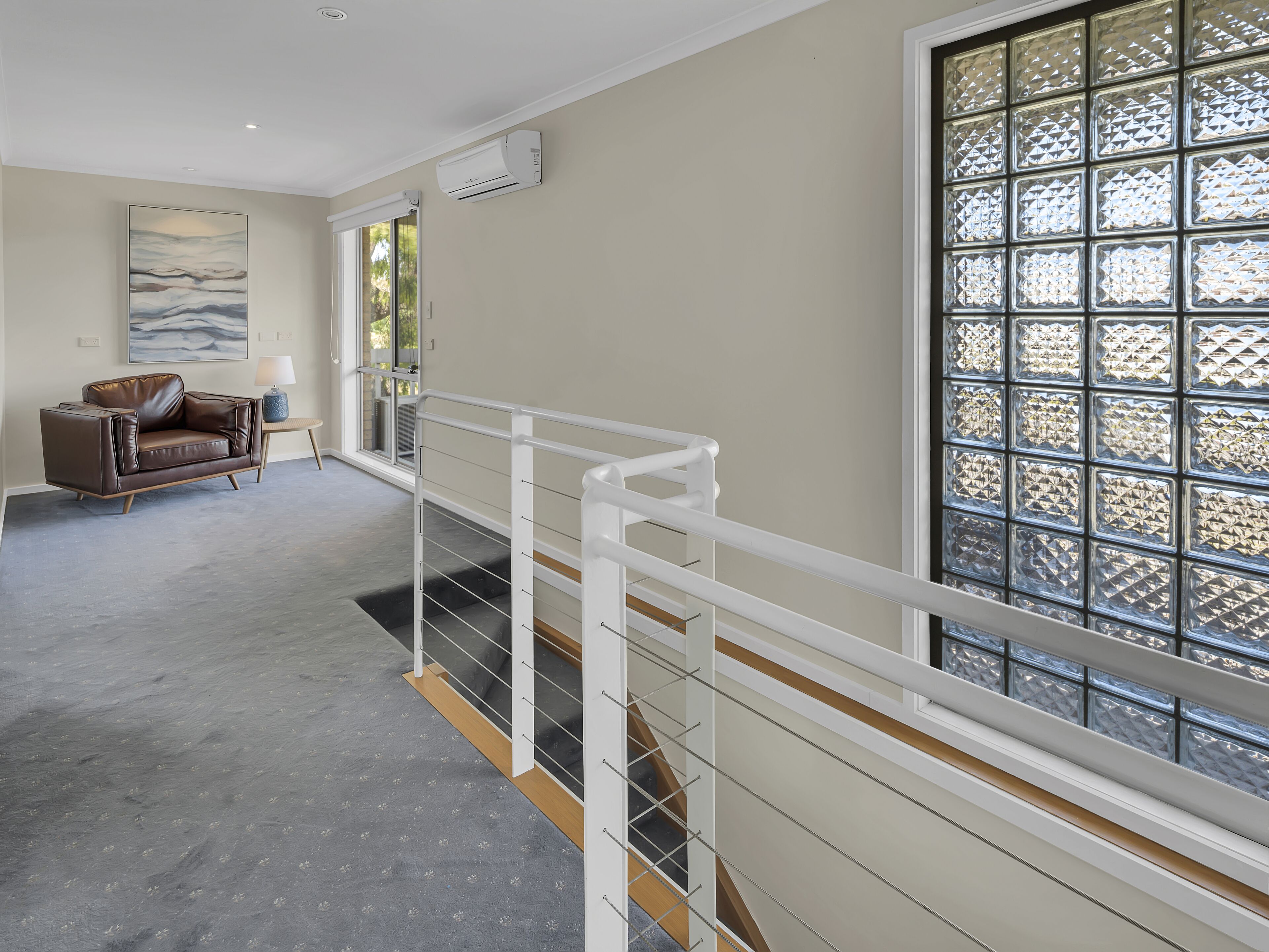 A spacious room with a large window, a sofa, and a staircase.