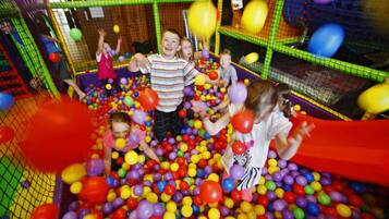 Children can play safely within this enclosed play area filled with colorful balls and balloons.