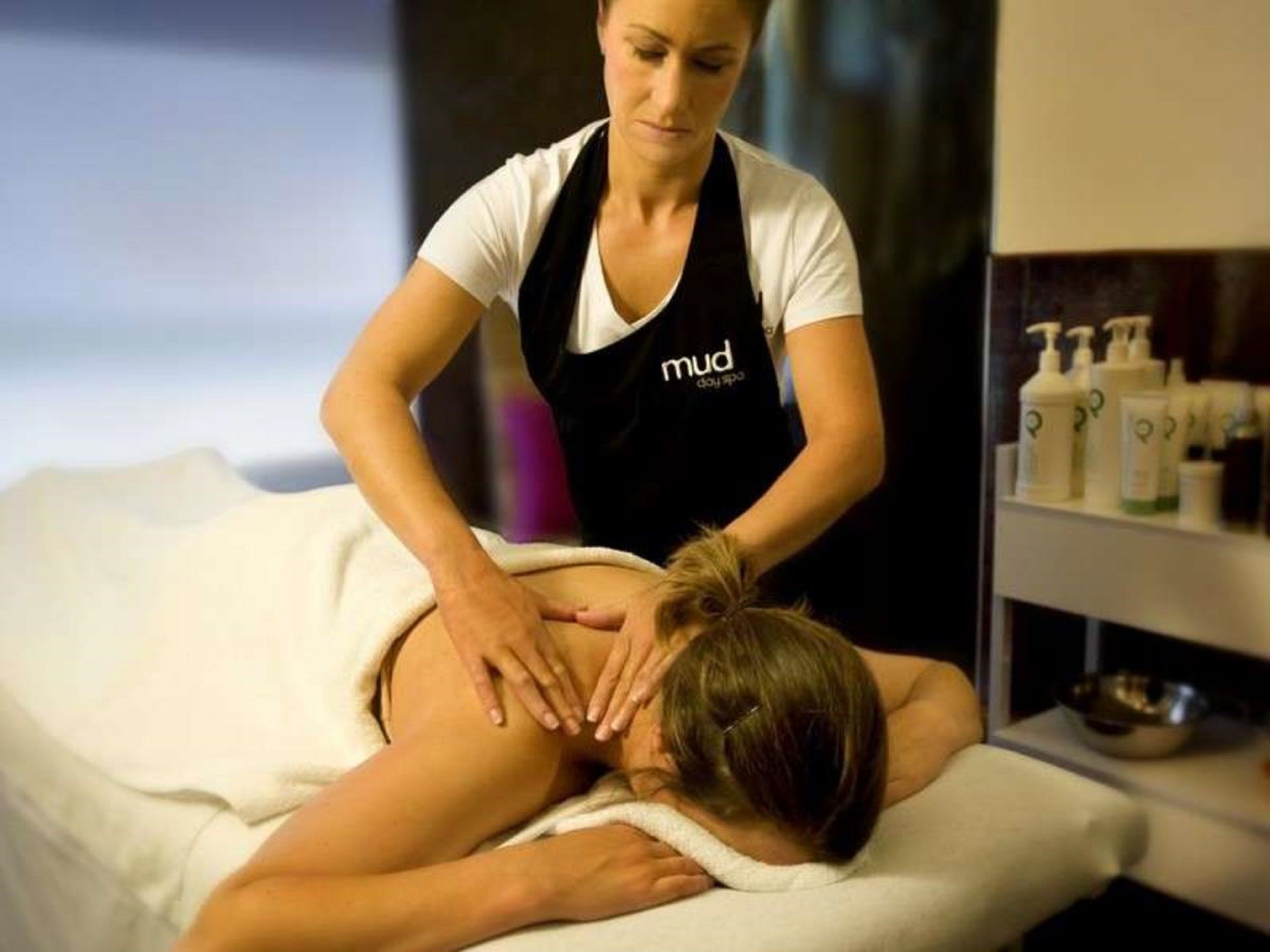 A massage therapy session in progress with a therapist and a client on a massage table.