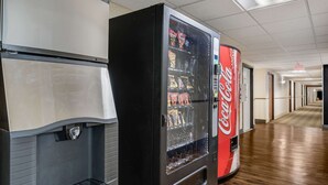 A vending machine with a Coca-Cola logo, a digital display, and a variety of snacks. - Econo Lodge Milwaukee Airport (Milwaukee)