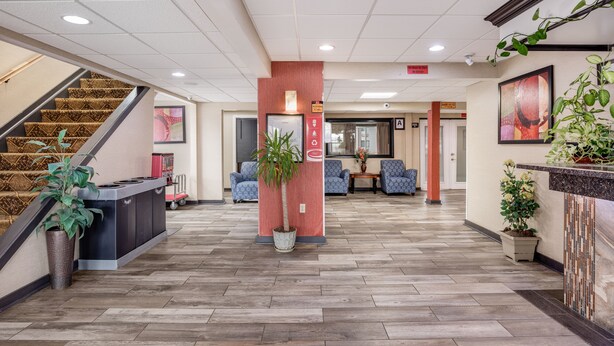 A hotel lobby with a reception desk, a staircase, seating area, and potted plants. - Econo Lodge Milwaukee Airport (Milwaukee)