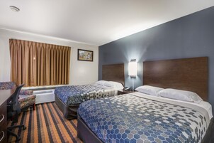Habitación de hotel con dos camas, un escritorio y una silla.