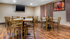 A conference room with wooden tables and chairs, a flat-screen TV, and a colorful abstract painting on the wall. - Econo Lodge Milwaukee Airport (Milwaukee)