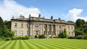 A large, historic building with a symmetrical facade, multiple windows, and a well-maintained lawn in front. - Balbirnie House (Glenrothes)
