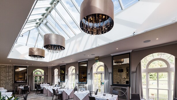 A spacious dining area with high ceilings, large windows, and elegant chandeliers. - Balbirnie House (Glenrothes)