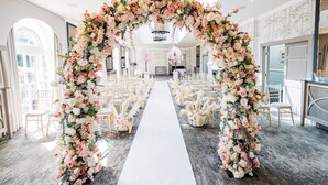 A wedding aisle with floral arches and white chairs on either side. - Balbirnie House (Glenrothes)