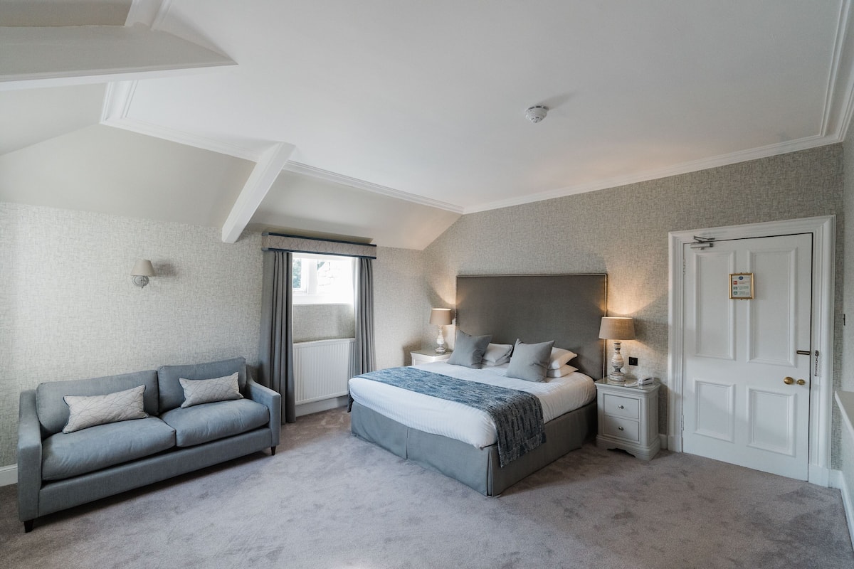 A bedroom with a bed, nightstands, a sofa, and a door.