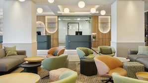 En modern entréhall med en receptionsdisk, bekväma sittplatser och dekorativ väggkonst.