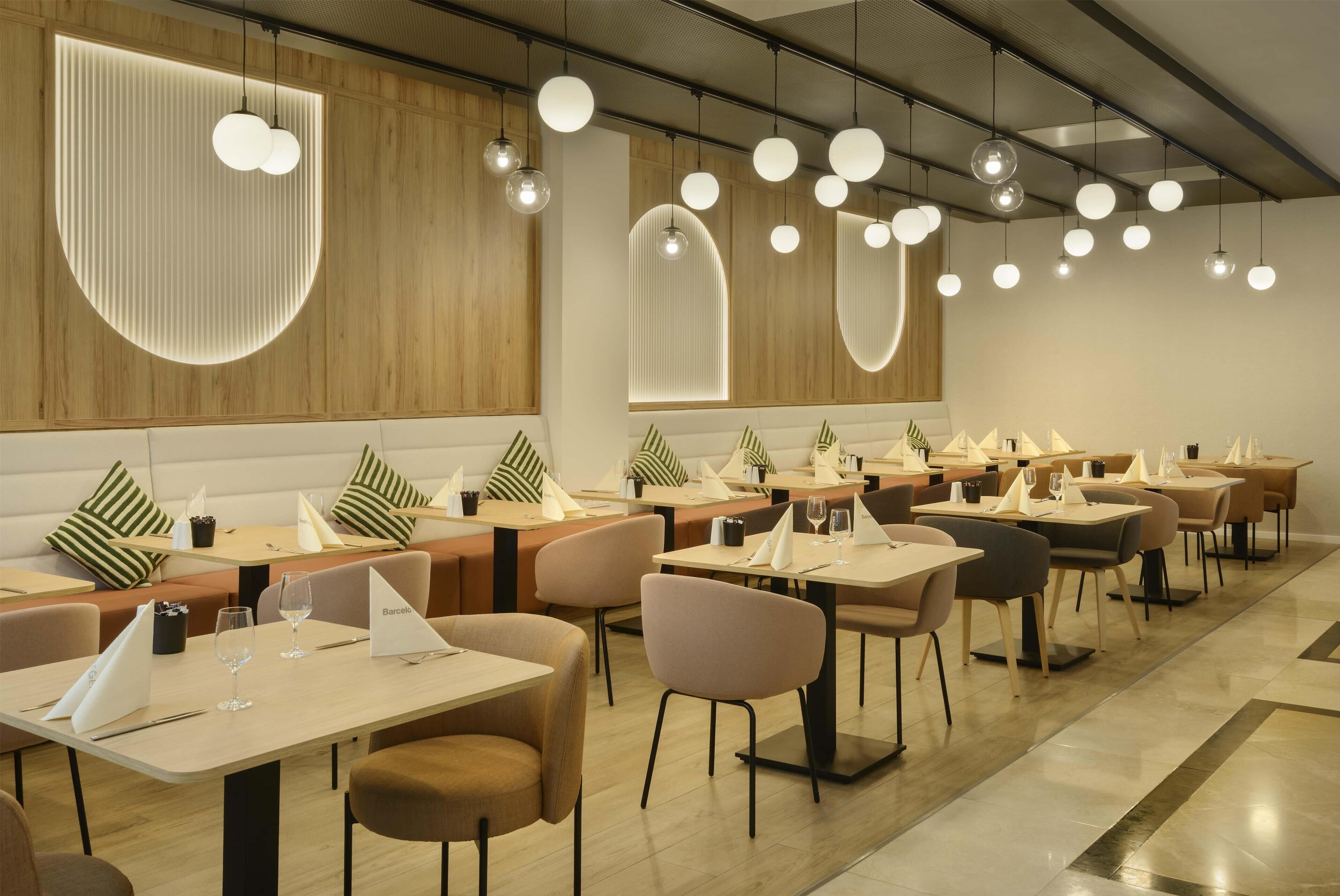 Ein modernes Restaurant mit mehreren Esstischen, Stühlen und Pendelleuchten.