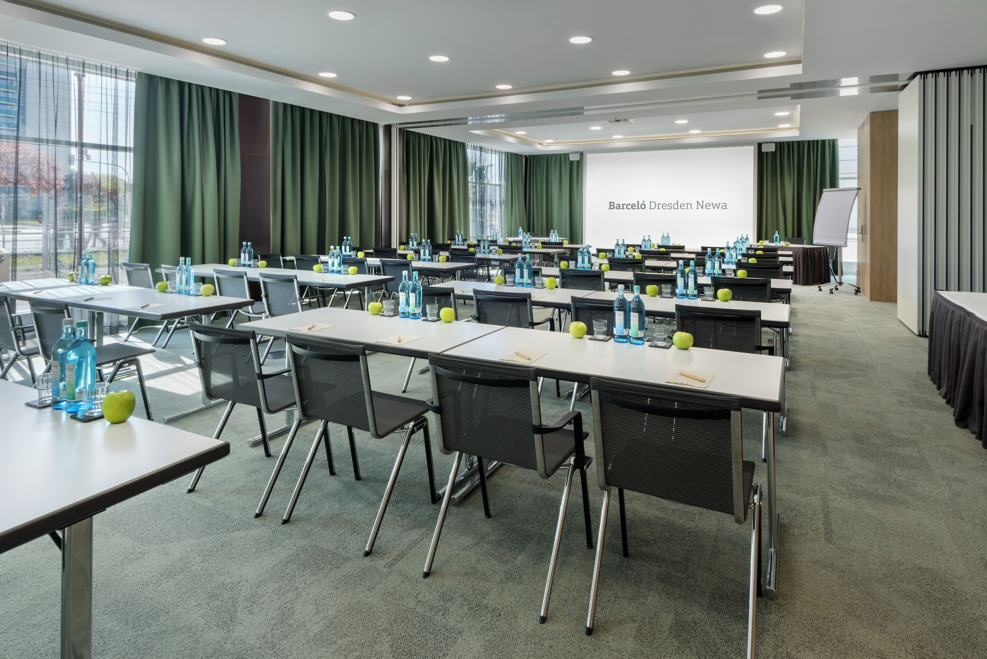 A conference room with tables, chairs, and a presentation screen.