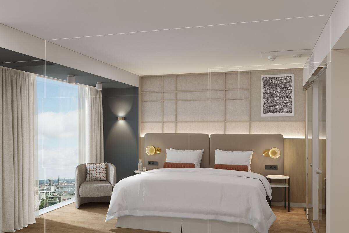 A modern hotel room with a large bed, a seating area, and a city view.