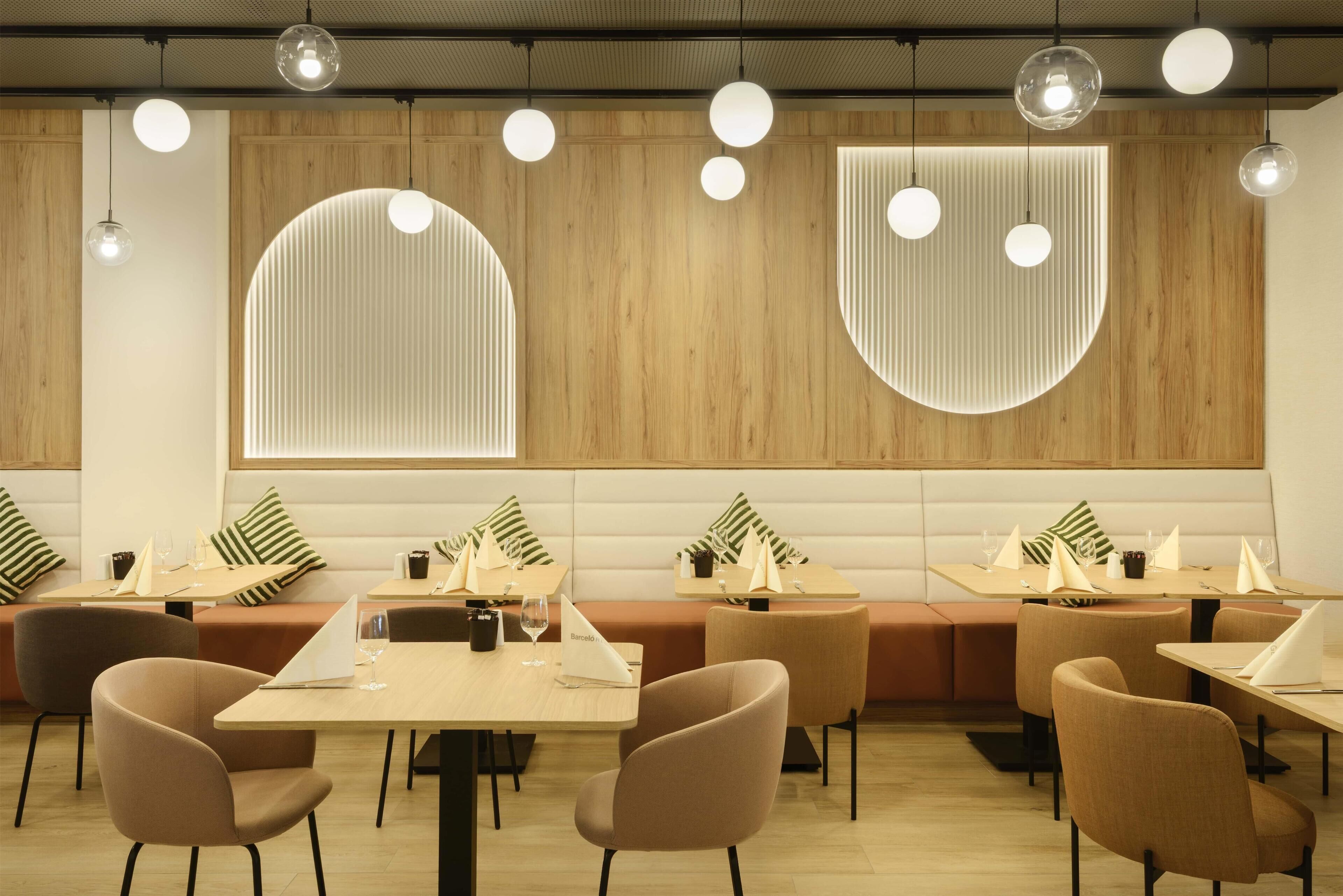 Un interior de restaurante moderno con mesas redondas, asientos acolchados e iluminación colgante.