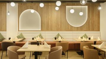 Un interior de restaurante moderno con mesas redondas, asientos acolchados e iluminación colgante.