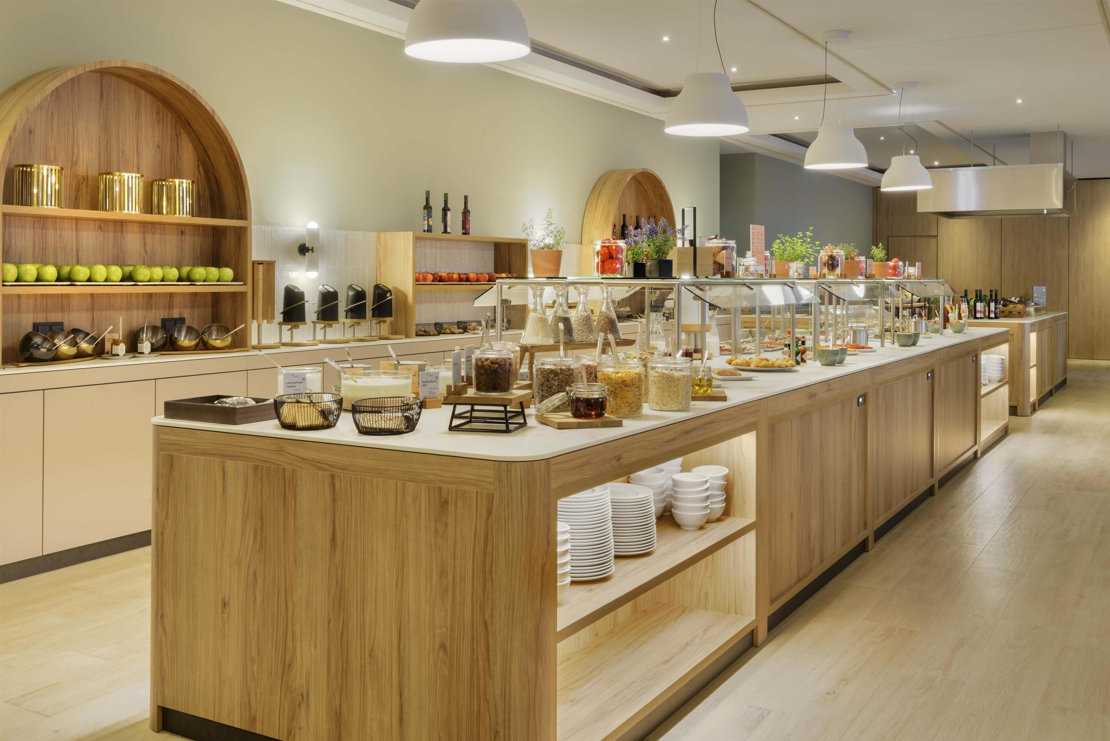 Una mesa de buffet con diferentes opciones de comida, una barra de madera e iluminación colgante.
