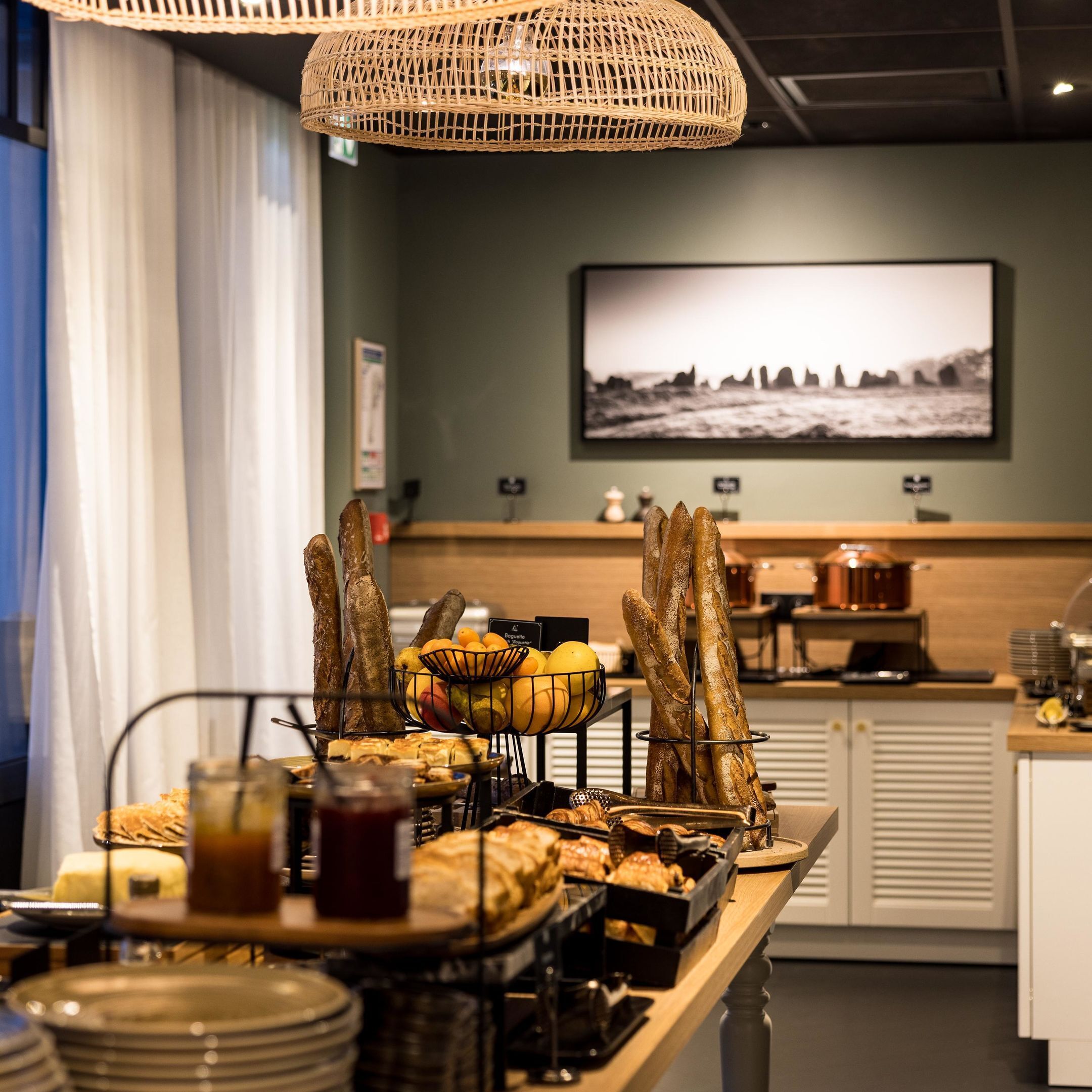 A breakfast buffet with baguettes, fruits, and pastries.
