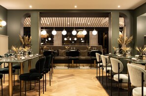 A modern dining area with a long table, multiple chairs, and a sofa in the background. - Le Celtique & Spa (Carnac)