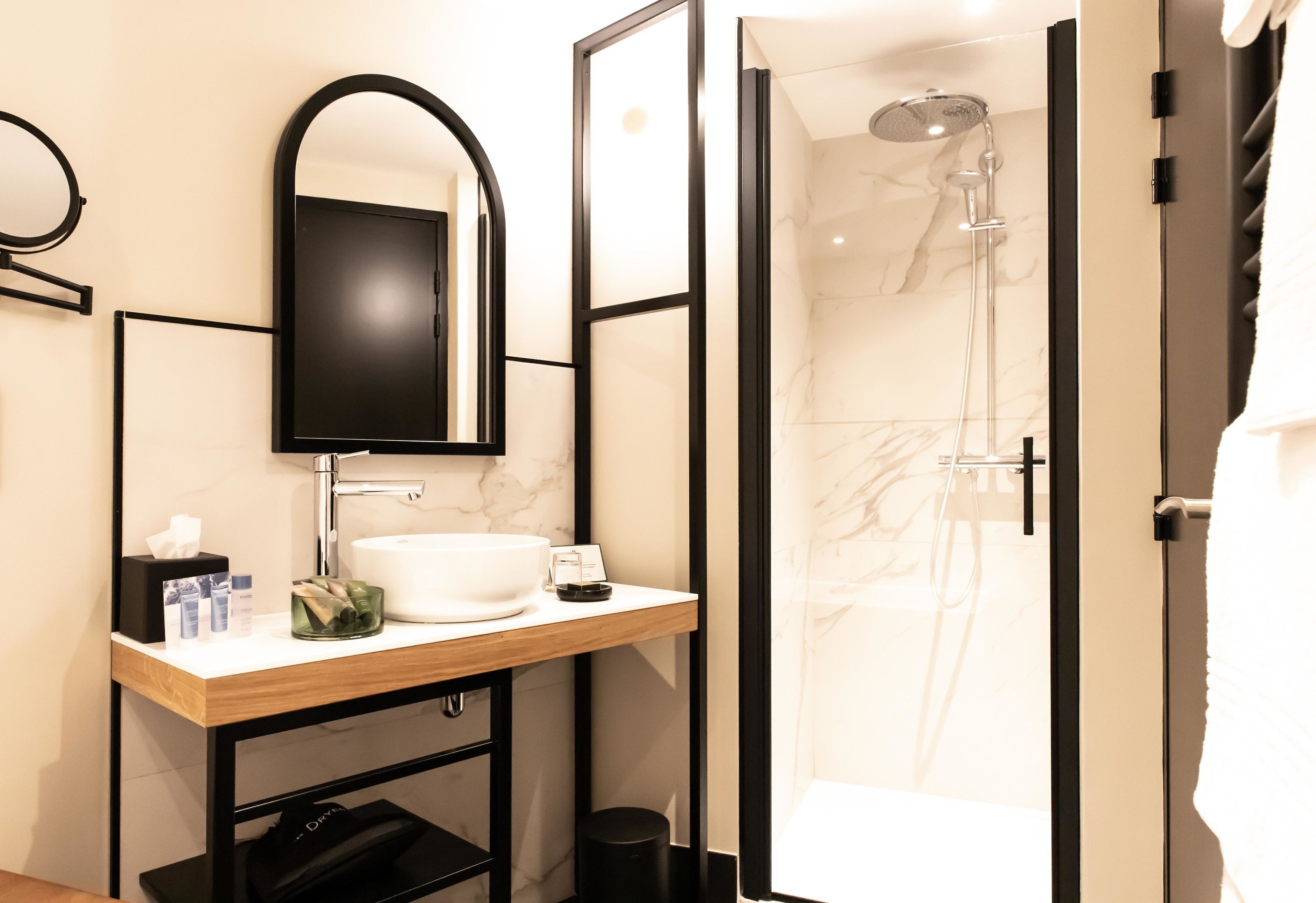 Een moderne badkamer met een grote spiegel, een wastafel en een douchehoek.