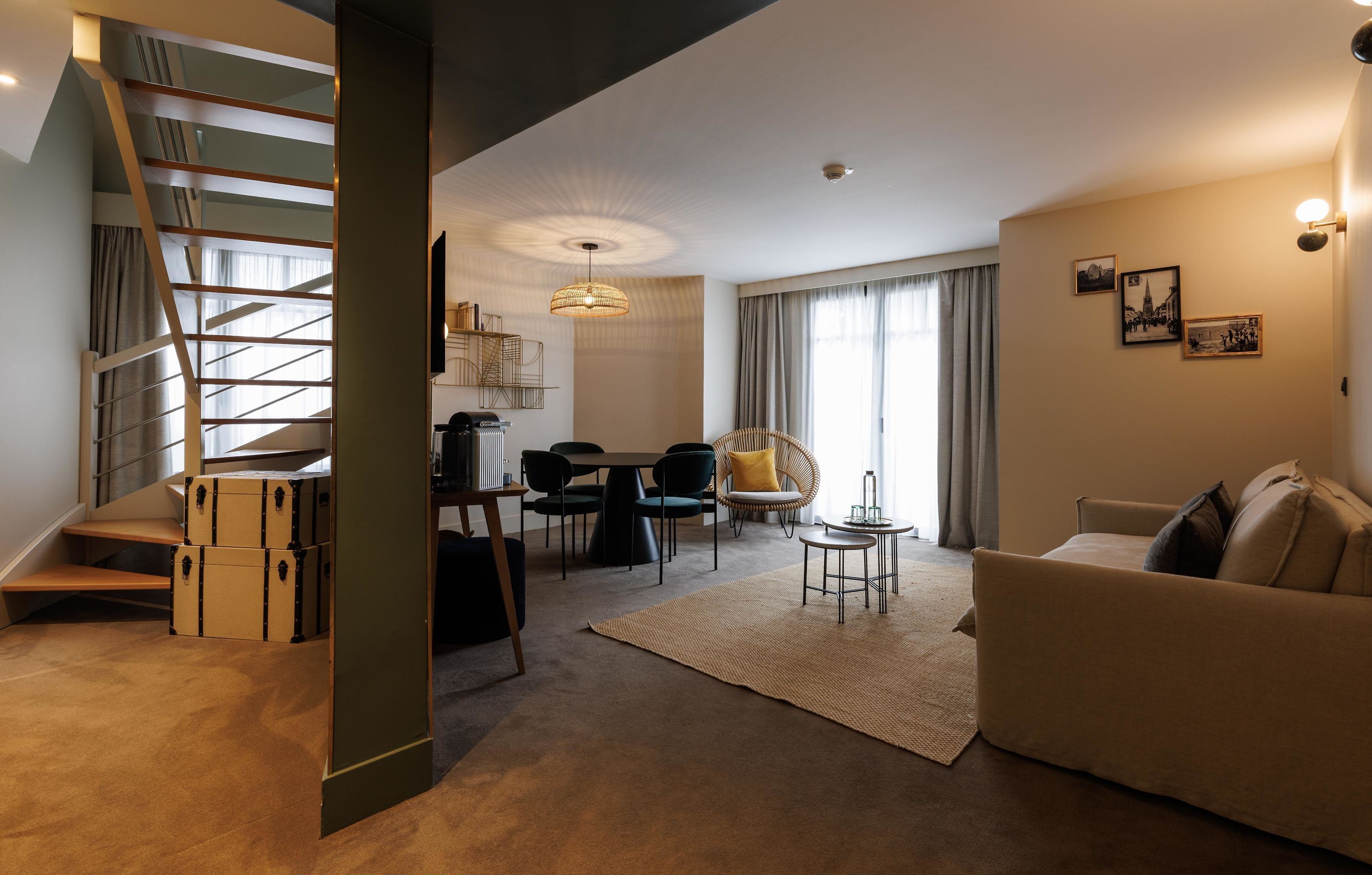 Een moderne woonkamer met een trap, een eethoek en een bank.