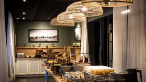 A buffet setup with various food items and beverages, a large framed picture on the wall, and a modern interior design. - Le Celtique & Spa (Carnac)