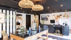 A modern kitchen with a black countertop, wooden table, and hanging wicker chandeliers. - Le Celtique & Spa (Carnac)