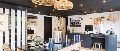 A modern kitchen with a black countertop, wooden table, and hanging wicker chandeliers.