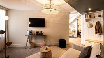 A modern living room with a flat-screen TV, a coffee machine, and a wicker basket.