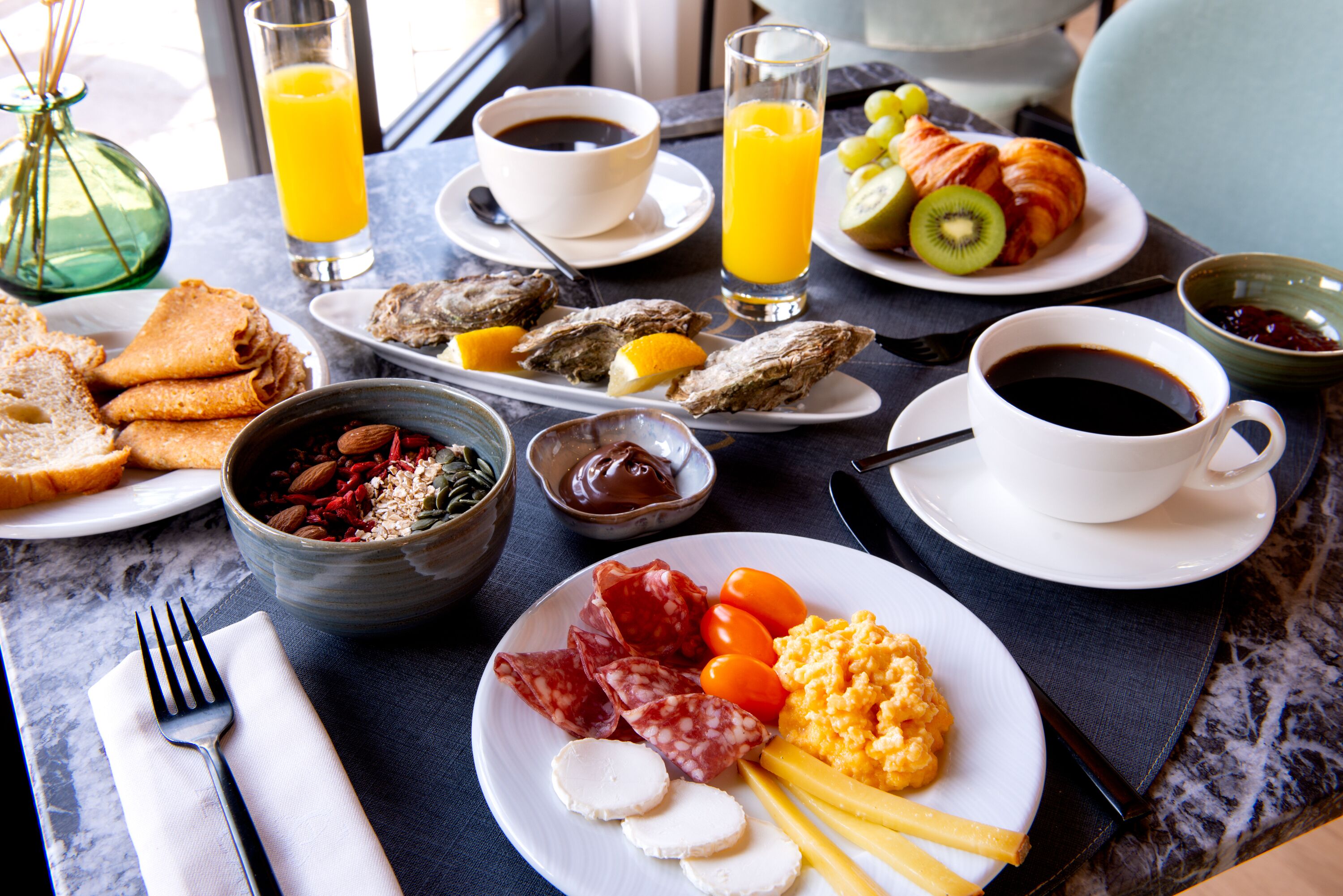 Una mesa de desayuno con diversos alimentos, como huevos, salchichas, queso y frutas.