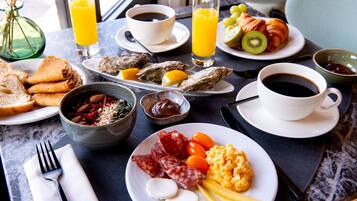 Una mesa de desayuno con diversos alimentos, como huevos, salchichas, queso y frutas.