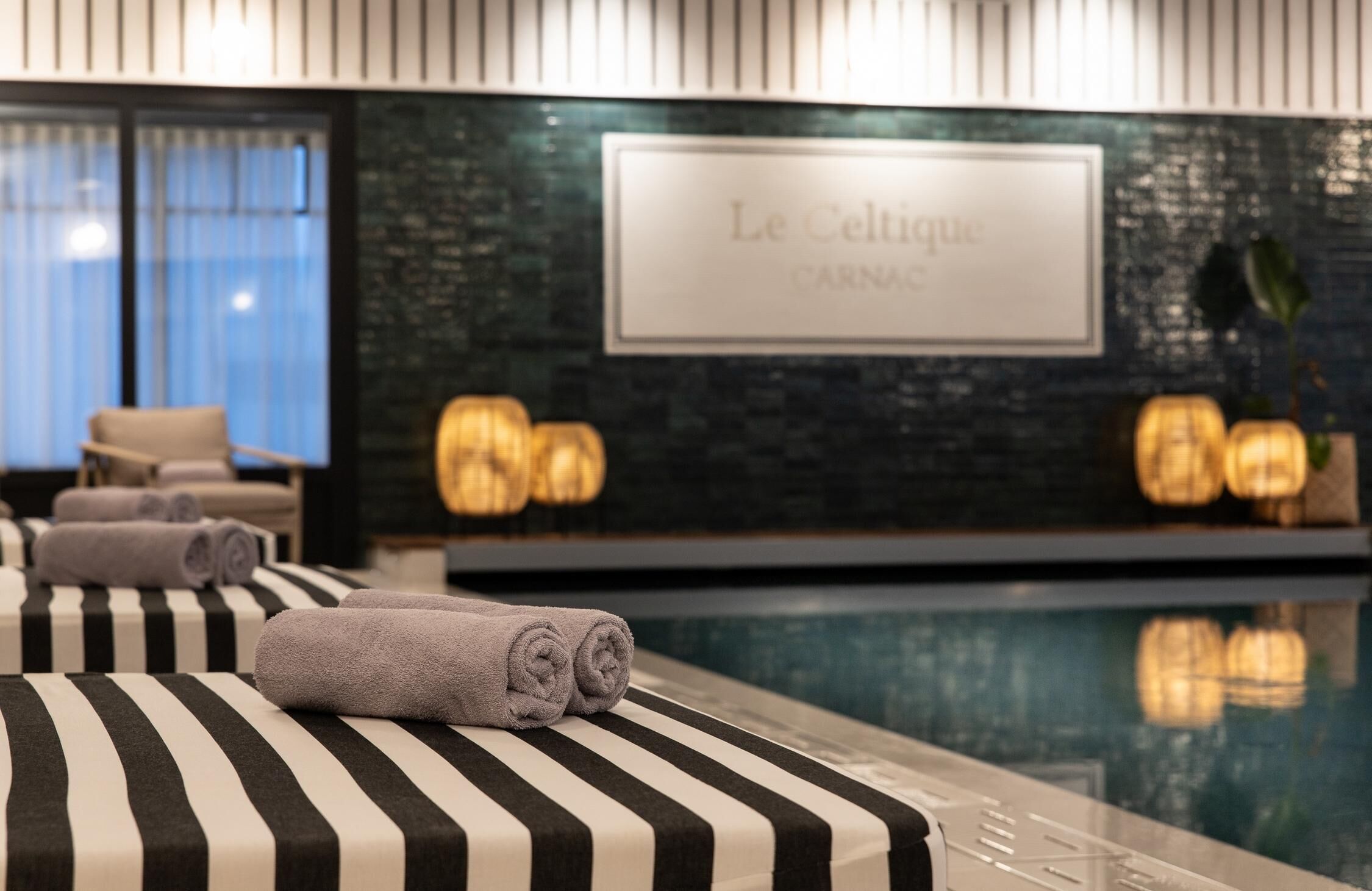 Une chambre d’hôtel avec piscine, des serviettes à rayures et une enseigne indiquant « Le Celtic Carnac ».