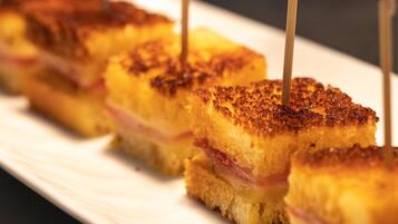 A series of square sandwiches with toothpicks, arranged on a white plate.