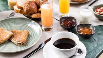 A breakfast setting with croissants, toast, juice, coffee, and jam.