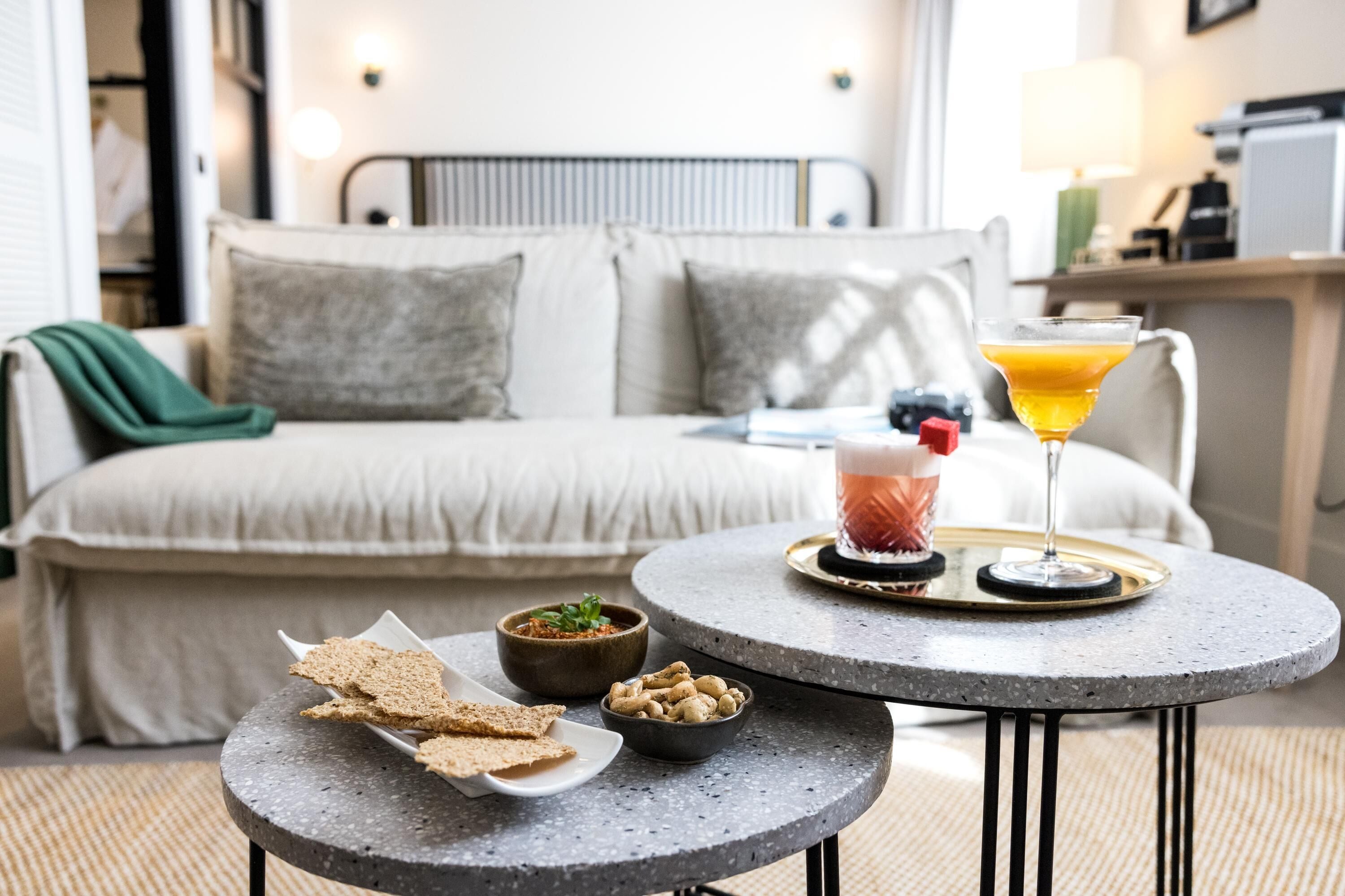 Acogedora habitación de hotel con cama, una pequeña mesa redonda con aperitivos y una bebida, y vista al interior de la habitación.