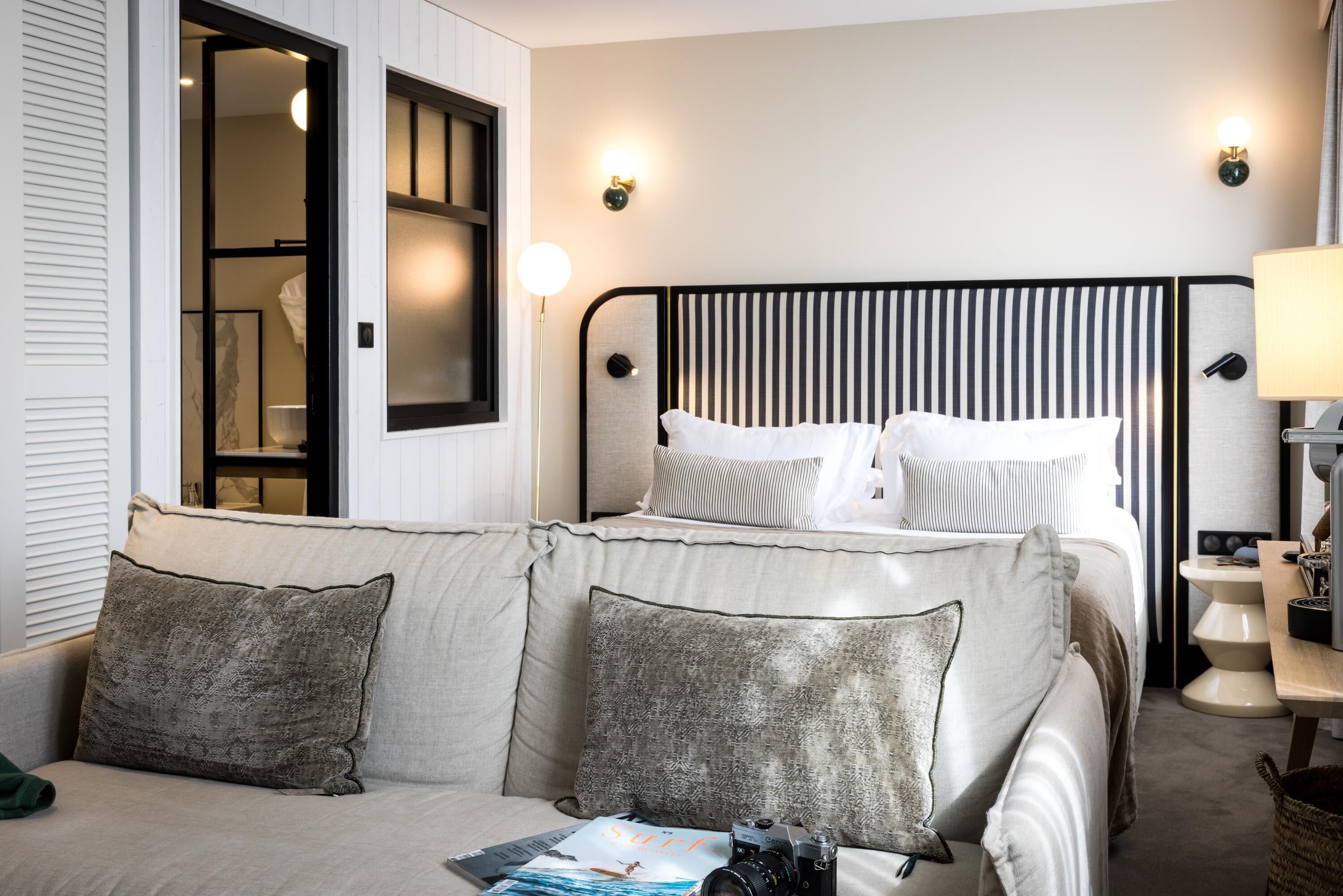 Una habitación de hotel con cama, sofá, lámpara y una cámara sobre el sofá.