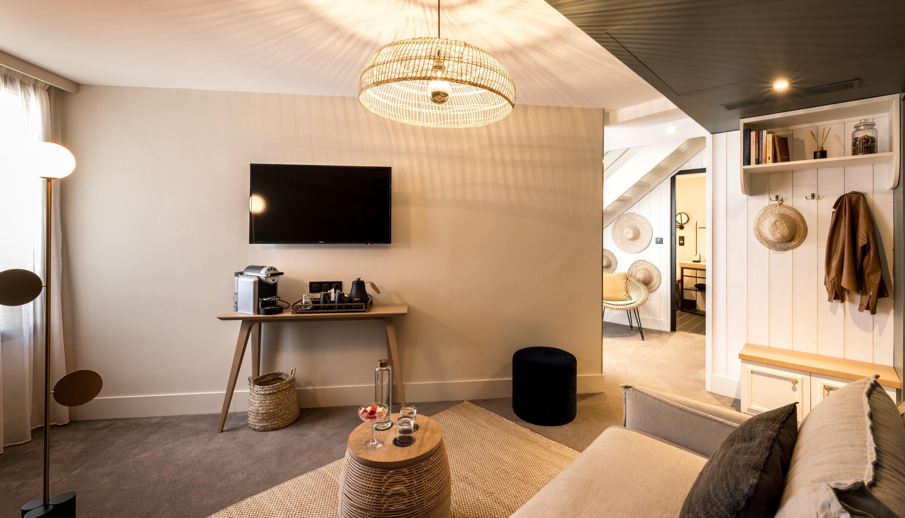 Een moderne woonkamer met een flatscreen televisie, koffieapparaat en een rieten mand.