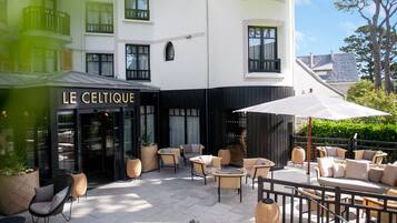 An outdoor seating area with wicker furniture and a sign reading "LE CELIQUE".