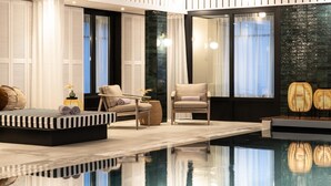 A modern indoor pool area with seating and a glass wall. - Le Celtique & Spa (Carnac)