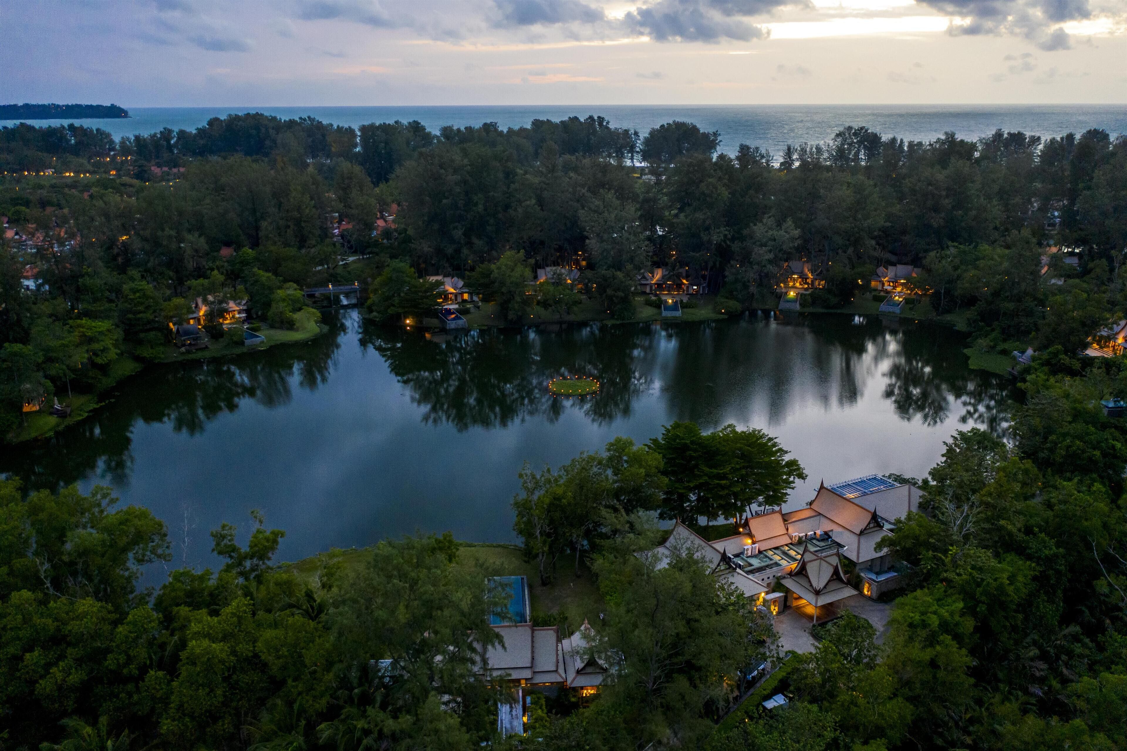 Un resort a orillas del lago con varias construcciones, un muelle y vistas al lago y la costa distante.