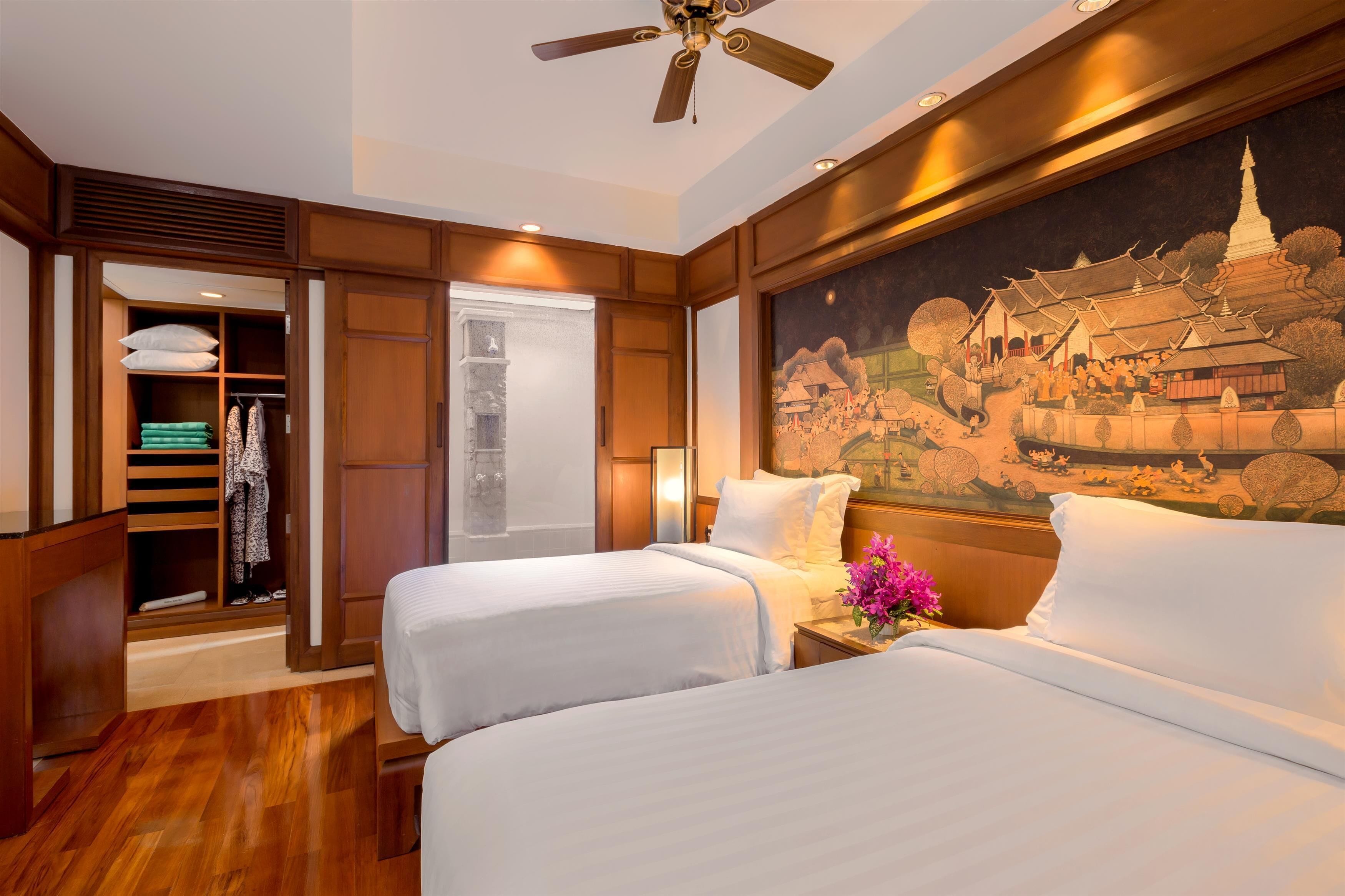 A hotel room with two beds, a wardrobe, and a mural of a temple.