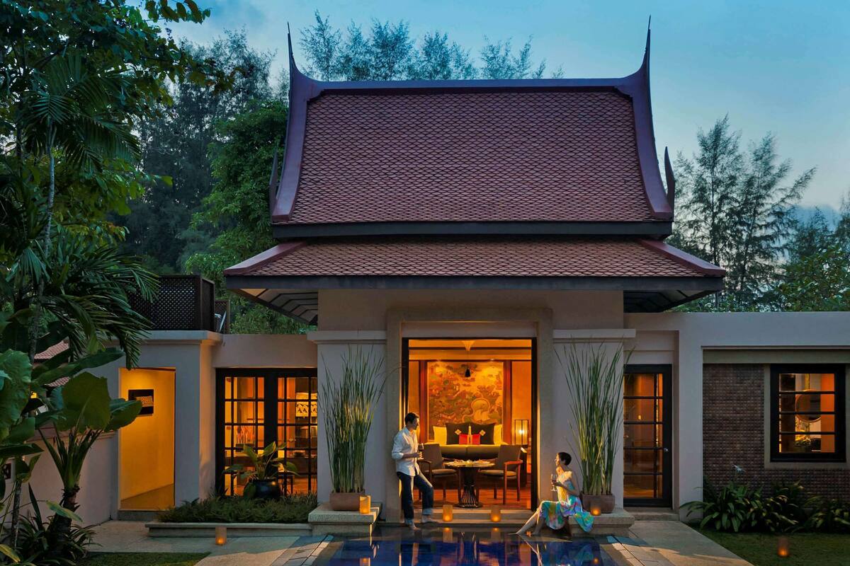 A modern building with a traditional roof, a swimming pool, and a well-maintained garden.