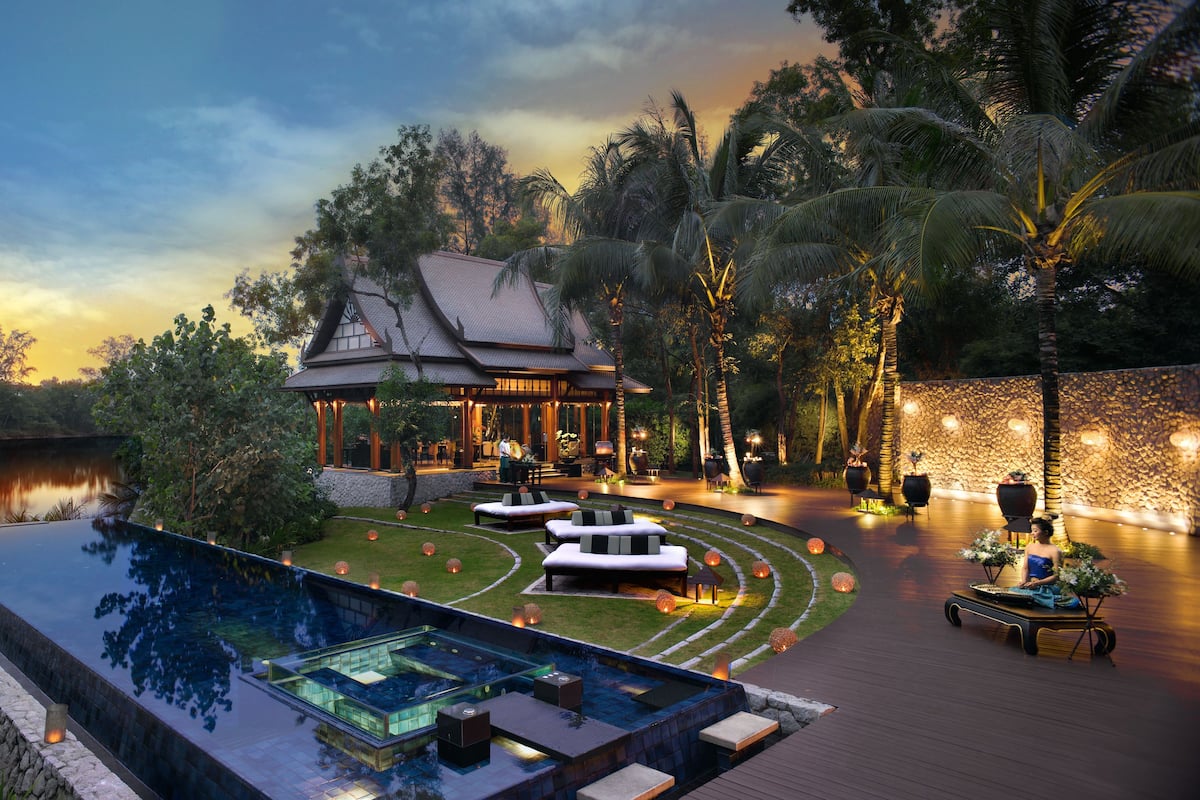 A luxurious resort with a large infinity pool, a well-maintained garden, and a traditional-style building.